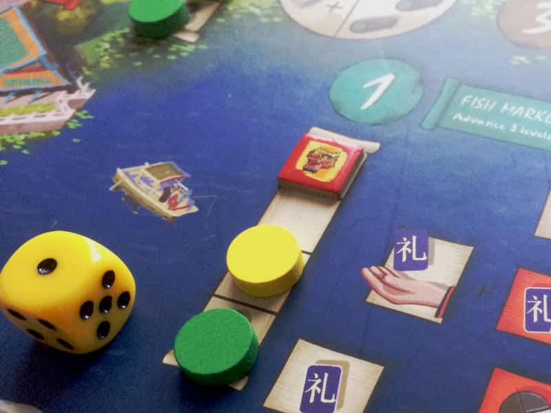 a yellow dice, a yellow wooden disc and a green wooden disc on a track on the Eternal Palace game board
