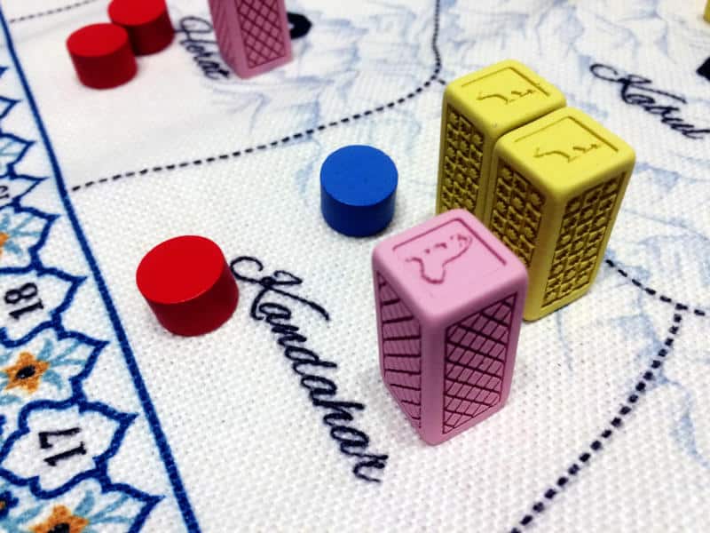two yellow and one pink resin block, three red discs and one blue one on the cloth game board