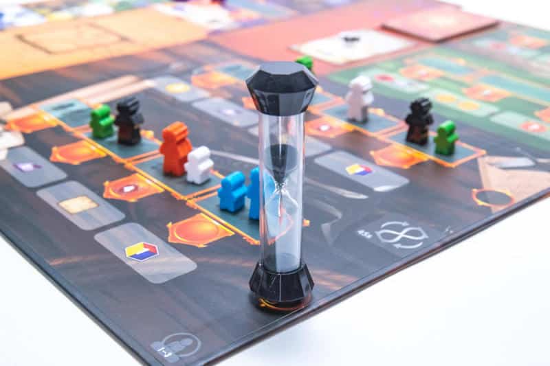 a sand timer, some meeples in different colours and the Pendulum game board (Photo courtesy of Stonemaier Games)