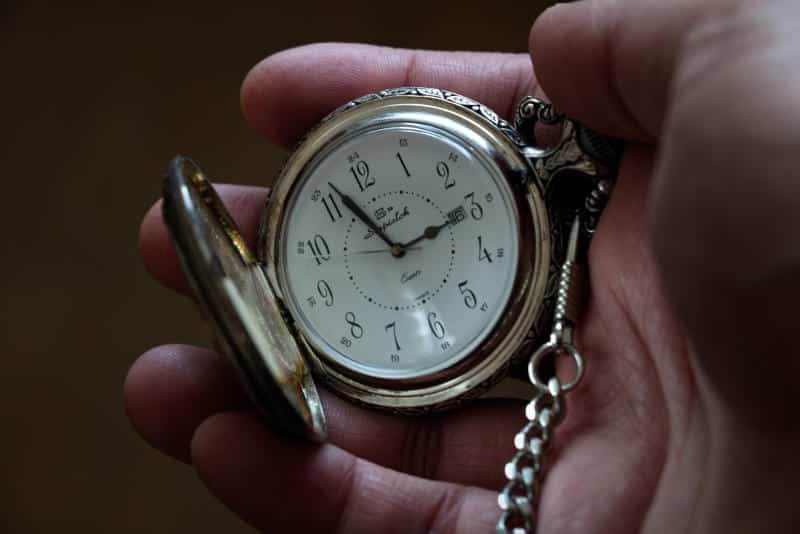 a pocket watch on a chain opened up in someone's hand (Photo by Pierre Bamin on Unsplash)