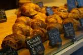 croissants and other pastries in a display with price labels