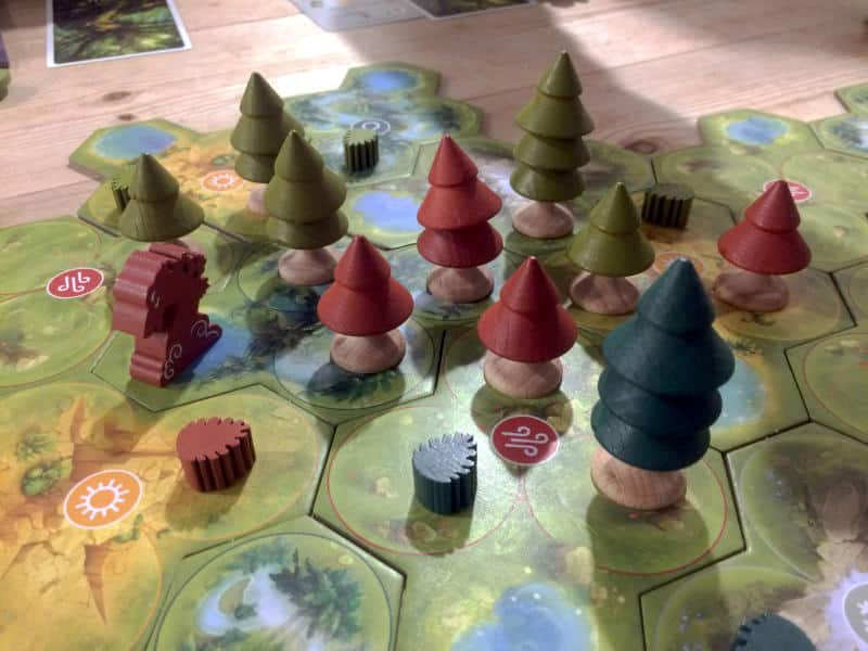 wooden trees and seed tokens on the modular cardboard map