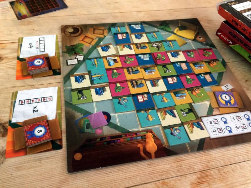 the central game board, the so-called living room floor, filled with tiles and two goal cards on one side