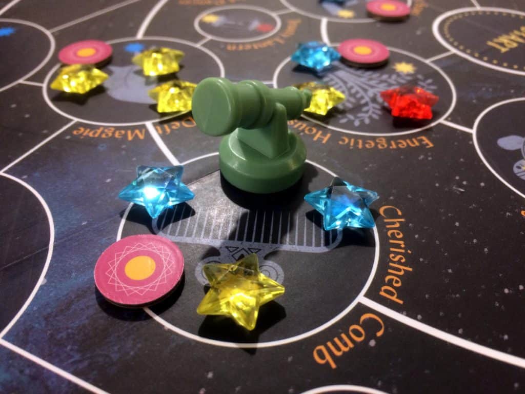 a close-up of one of the telescope miniature player token and the gem star tokens