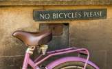 a pink pushbike undernath a sign saying "No Bicycles Please"