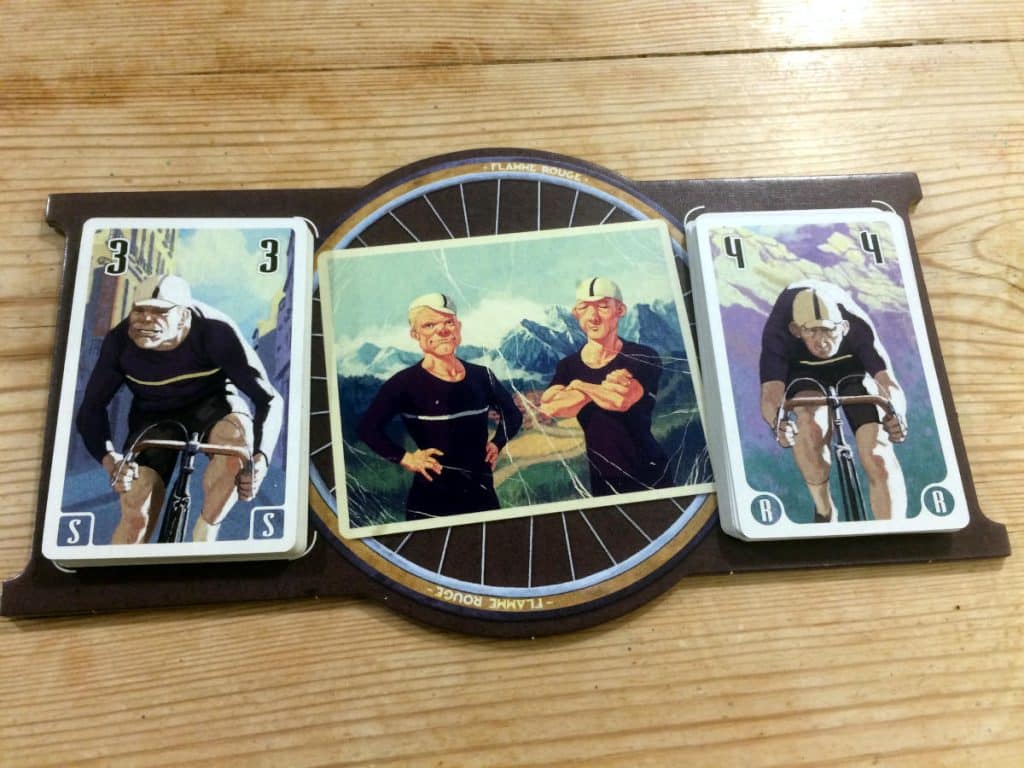 two decks of cards one black player board featuring cartoon illustrations of bicycle riders