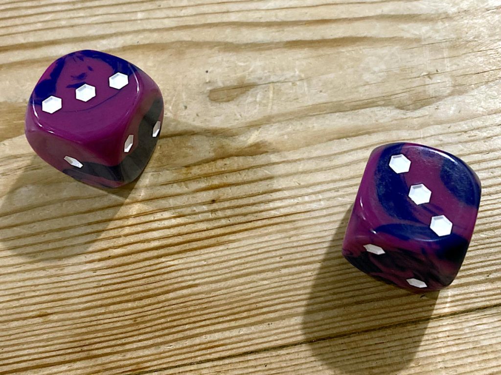 two purple, plastic dice showing three