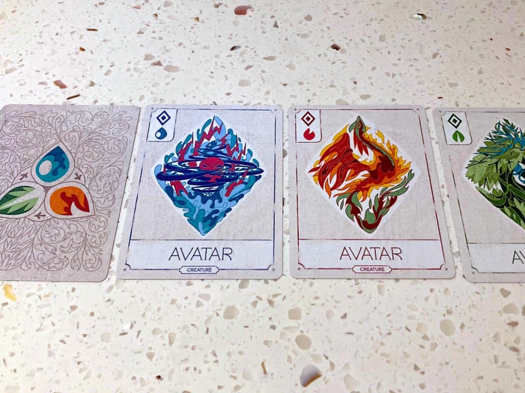 the three Avatar cards and a face-down card showing the back lying side-by-side on a worktop