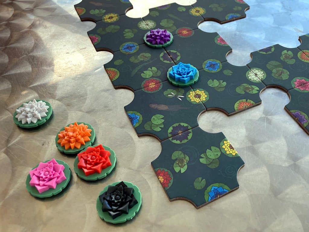 some of the tiles and tokens from A Gentle Rain laid out on a silver topped table