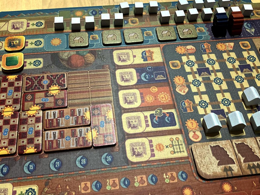 a player board with textile tiles, Tambo tokens, terrace farming cubes, and more