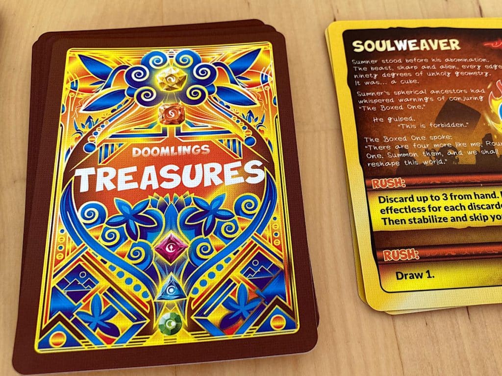the deck of Treasures cards from Doomlings: Legends of Enderas on one side with one card face-up next to it