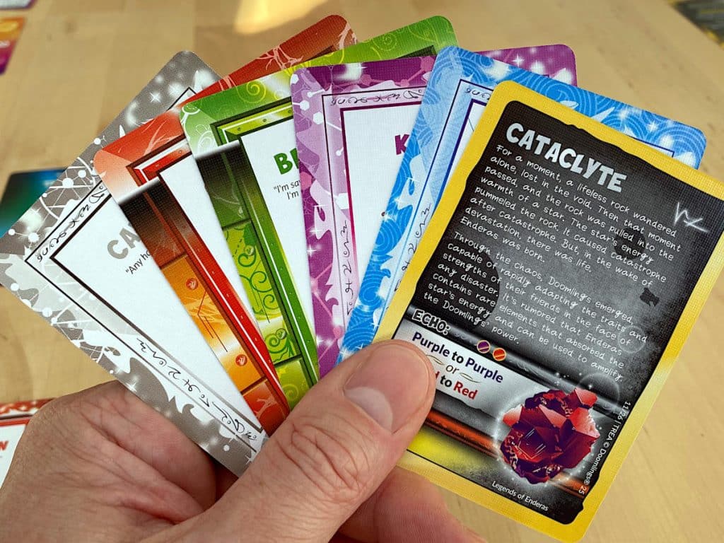 a fan of cards from Doomlings: Legends of Enderas held between thumb and index finger